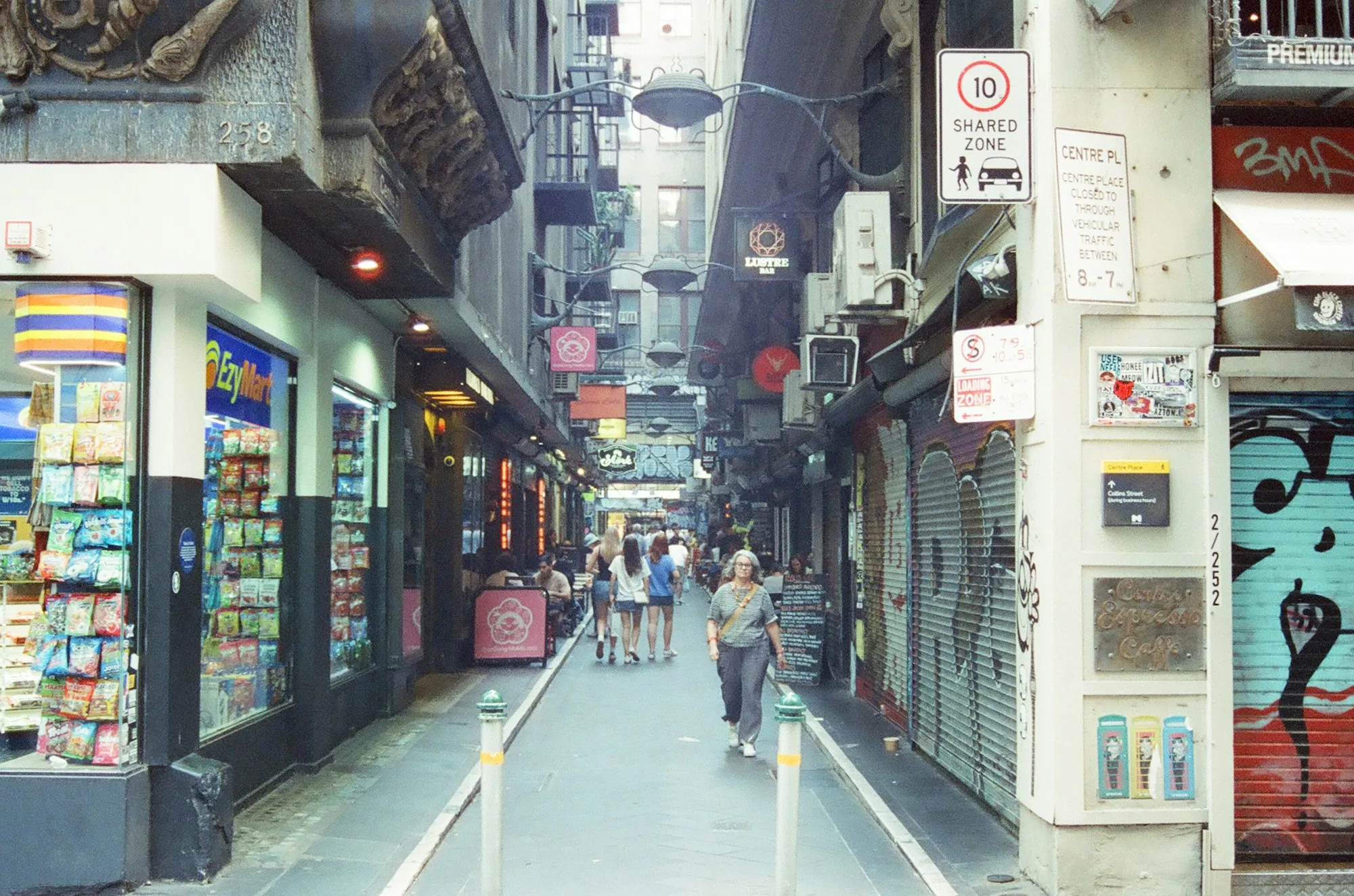 People walking down a narrow city laneway lined with small shops